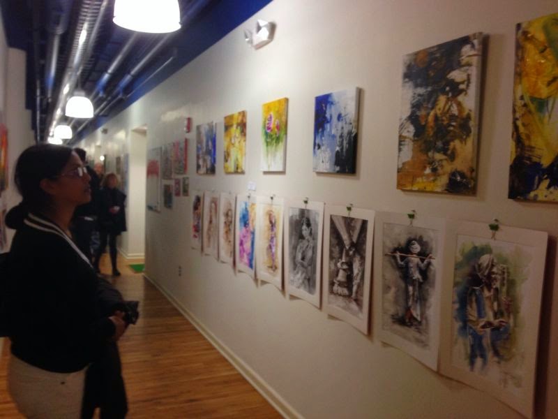 A long gallery corridor with oil paintings above a row of drawings and watercolors