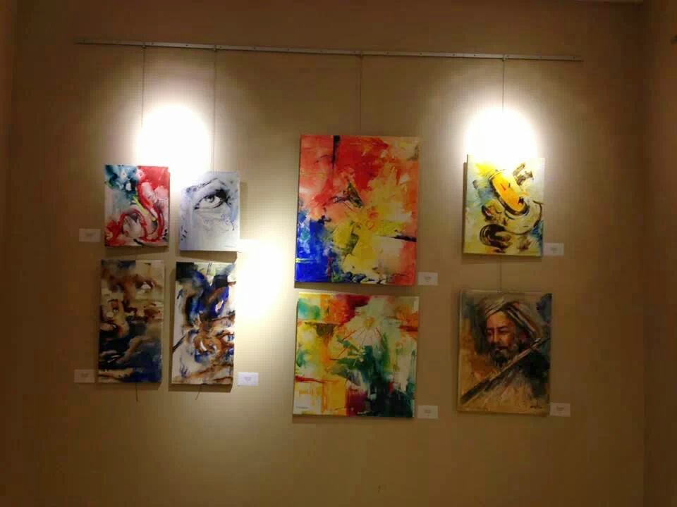Abstract canvases and a portrait of a bearded figure hanging in a gallery