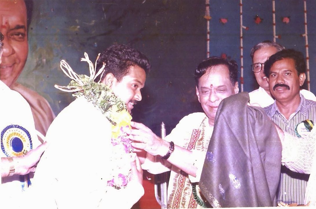 Sri Mangalampalli Balamuralikrishna draping a shawl on Jaya Krishna Bandari during an honor ceremony